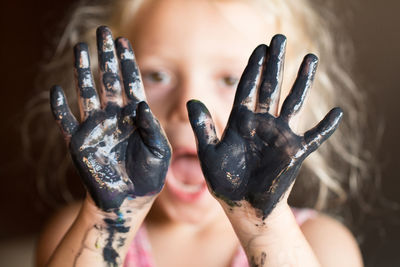 Front view of girl  holding up dirty hands