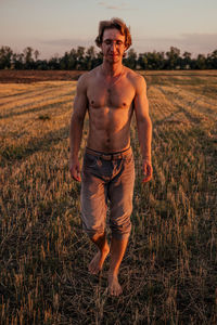 Portrait of shirtless man standing on field