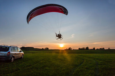 Low angle view of person paragliding against sky during sunset