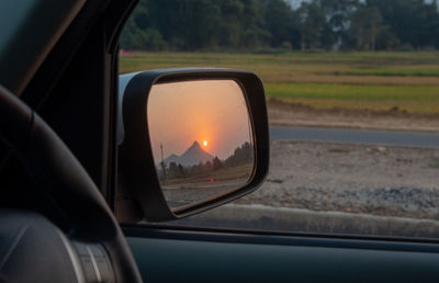 Reflection of sunset in side-view mirror