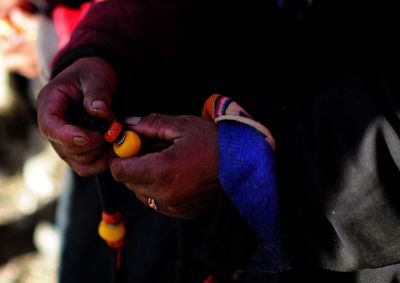 Midsection of person holding beads with rope