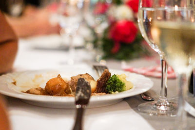 Close-up of meal served by wine glasses on table