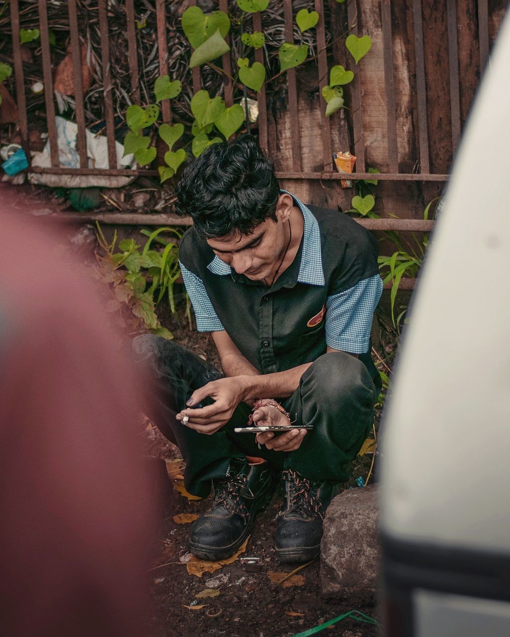 one person, real people, men, focus on background, lifestyles, holding, adult, casual clothing, occupation, young adult, selective focus, mid adult men, day, full length, looking, working, sitting, males, hand, outdoors