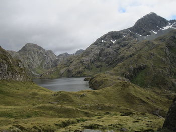 Scenic view of mountains and lake against cloudy sky