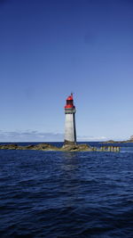 Lighthouse by sea against clear sky