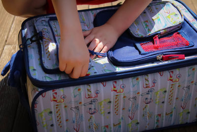 Cropped hands of child holding luggage