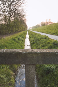 Road amidst field against clear sky