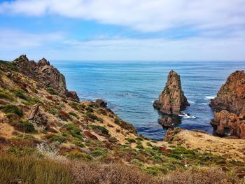 Scenic view of cliff by sea against sky