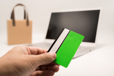 Cropped hand of woman using digital tablet against white background