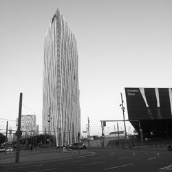 Road by buildings against clear sky