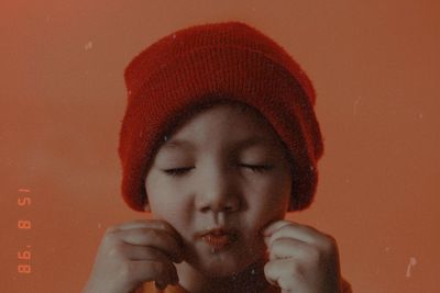 Close-up portrait of boy drinking glass against red background