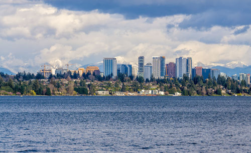 Sea by buildings against sky in city