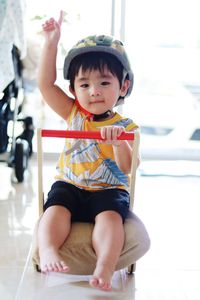 Full length portrait of cute boy on toy at home