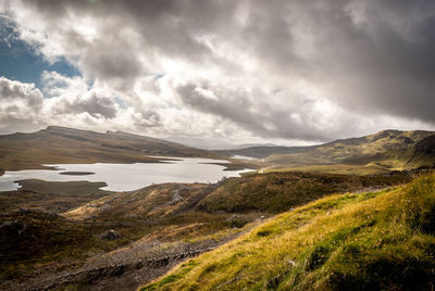 Scenic view of lake and mountains against cloudy sky