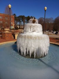 Water fountain in city against sky during winter