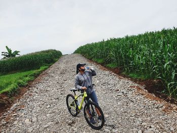 Man riding bicycle on road amidst field