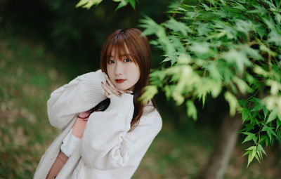 Portrait of young woman standing against plants