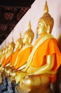 Row of golden buddha statue against temple