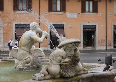 Statue by fountain against building