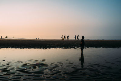 Silhouette man standing on beach against clear sky