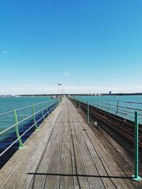 Pier over sea against clear blue sky