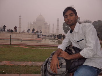 Men sitting at temple against sky during sunset