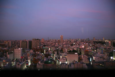 Illuminated cityscape against sky at night