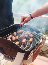 Grilled sausages. closeup of a man's hand put the sausages on the grill.