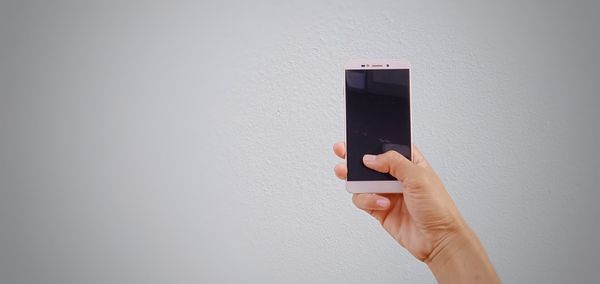 Midsection of person holding umbrella against white wall