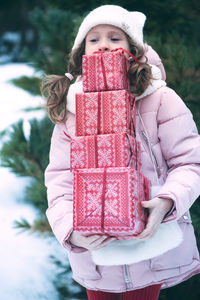 Girl carrying red gift boxes during winter