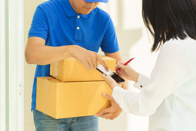 Woman signing on smart phone while receiving cardboard boxes