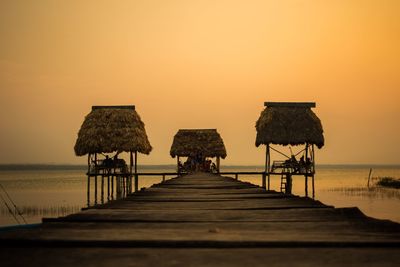 Pier over sea against sky during sunset