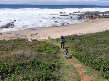 Rear view of men walking on beach