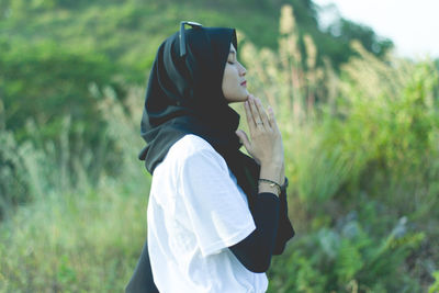 Side view of young woman standing on field