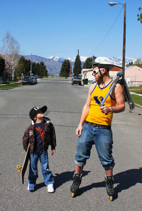 Full length of father and son at street on sunny day