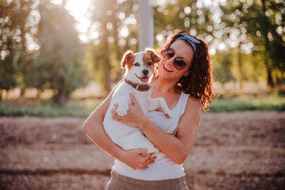 Woman with dog wearing sunglasses standing outdoors