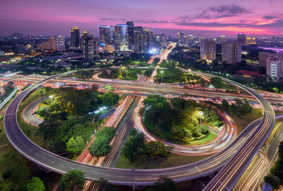 High angle view of light trails on road amidst buildings in city