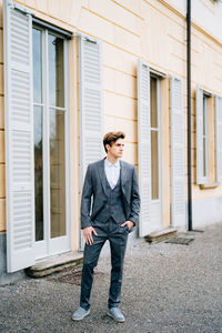 Young man looking away while standing against building