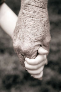 Cropped image of grandparent and grandchild holding hands