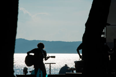 Silhouette people photographing sea against sky