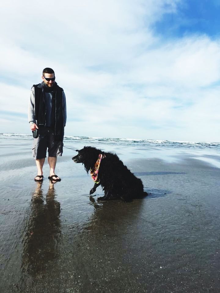 FULL LENGTH OF YOUNG WOMAN WITH DOG ON BEACH