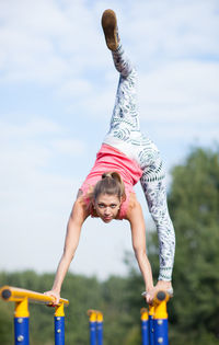 Portrait of woman balancing on railing against sky at park