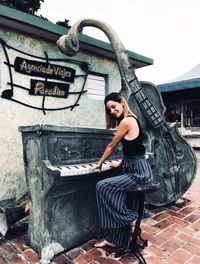 Full length portrait of woman standing against wall