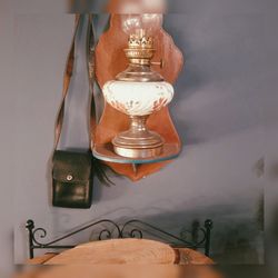 Low angle view of electric lamp on table against wall at home