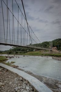 View of suspension bridge against cloudy sky