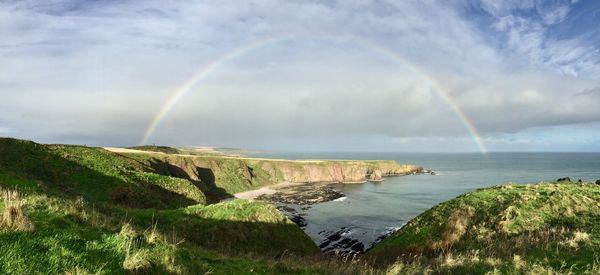 Scenic view of rainbow over sea against sky