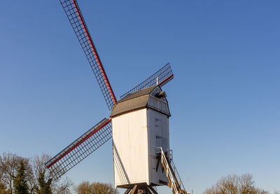 Low angle view of traditional windmill against clear blue sky