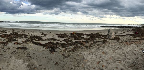 Scenic view of beach against cloudy sky