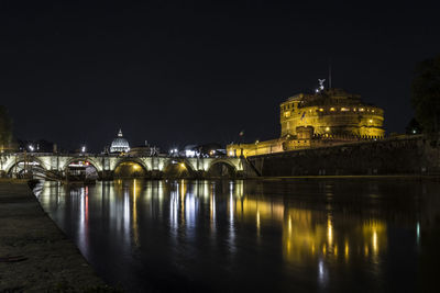 Illuminated buildings by river at night