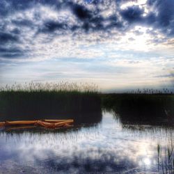 Scenic view of calm lake against cloudy sky